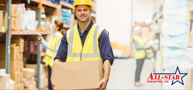 a temporary male warehouse worker carrying a box